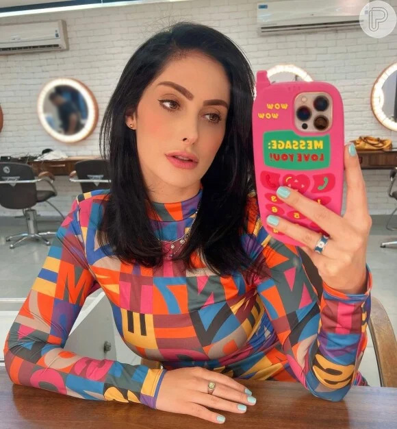 Francini Piaia posta selfie com roupa colorida e celular na mão.Apresenta seu onlyfans grátis com conteúdos quentes
